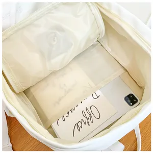 White canvas backpack interior detail view featuring spacious main compartment and mesh pocket.