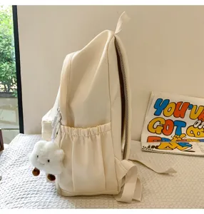 Minimalist beige canvas backpack detail with side pockets and a cute plush cloud charm.