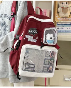 Mochila ita burdeos de lona con ventanas transparentes, chapas y bonito osito de peluche.