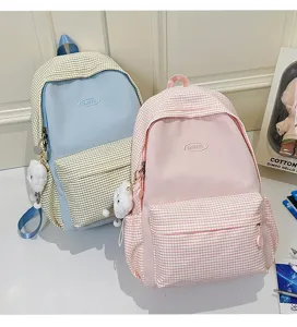 Close-up detail shot of cute plaid school backpacks featuring sweet pastel colors and plush doll.