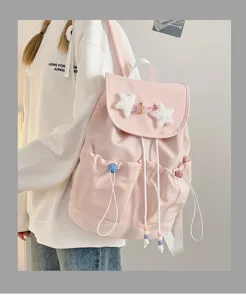 Detailed view of pink drawstring backpack with cute star plush charms and shoulder straps.