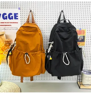 Detail view of large capacity nylon backpack, solid color school bag with drawstring pocket.