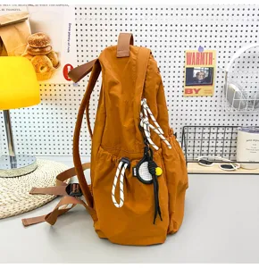 Detailed view of a stylish solid caramel nylon backpack with convenient drawstring and cute pendant.