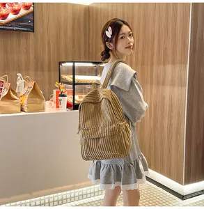 Detail view of stylish corduroy backpack worn by model in cafe, casual everyday fashion wear.