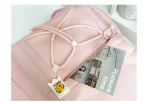 Pink backpack front pocket detail featuring elastic bungee cord and tag for daily school use.