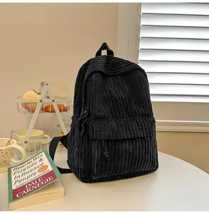 Detailed view of a black corduroy backpack featuring front pocket and adjustable straps.