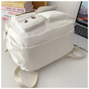 Detailed close-up view of white minimalist student backpack with multiple practical pockets.