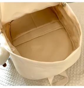 Detailed interior view of a minimalist solid color beige canvas school backpack with pockets.