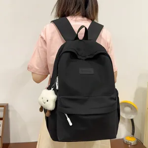 Minimalist black backpack for women, casual school bookbag for students with cute pendant.