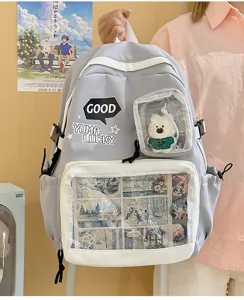 Vista detallada de mochila ita gris, bolsillo transparente con peluche y pines anime.