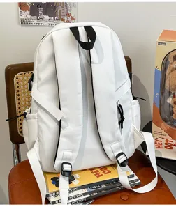 Vista detallada de la mochila blanca mostrando correas con ribetes negros y hebillas.
