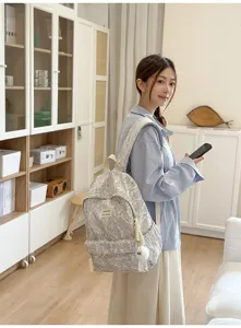 Detail view of a floral lace backpack worn by a model in a bright indoor room setting.