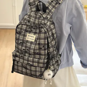 Japanese style plaid school backpack for women and students with cute furry pendant and casual design.