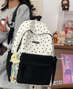 Cute white star print backpack with black front pocket and moon pendant for school daily use.