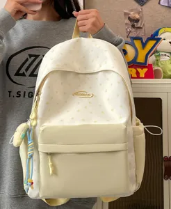 Detail view of casual white star print school backpack with front pocket and cute charms.