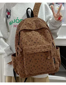 Detailed view of brown corduroy backpack with cute heart and bow print, front pocket design.