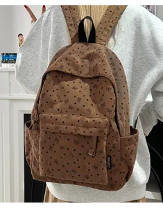 Brown corduroy backpack with cute heart bow prints, detail view showing front pocket and tag.