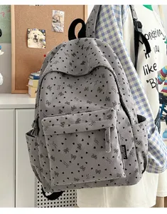 Detail of grey corduroy backpack featuring cute heart bow print and convenient front pocket.