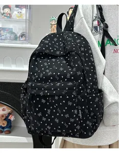 Black corduroy backpack with cute white heart pattern, detail view showing strap.