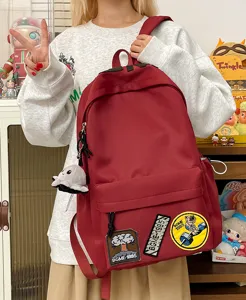 Large capacity red casual school backpack with trendy patches and cute doll pendant for daily use.