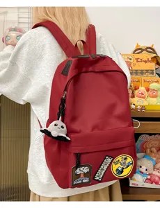 Red aesthetic canvas school backpack with cute plush charm and indie patches for daily use.