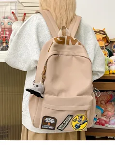 Detailed view of casual beige backpack with trendy patches and large capacity for daily use.