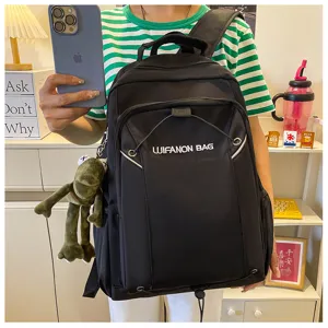 Detailed view of black waterproof school backpack with front pocket and hanging doll.