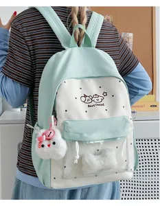 Close up detail view of cute mint green polka dot backpack with clear front pocket and plush charm.