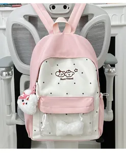 Pink polka dot backpack with clear front pocket, cute plush pendant and bow detail.