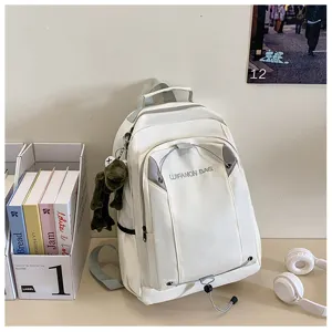 White casual backpack detail view with front drawstring and cute frog keychain for students.