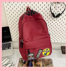 Detail shot of a large-capacity red canvas backpack with trendy patches and front pocket.