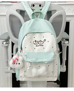 Detailed view of mint green and white canvas backpack with clear pocket and cute charms.