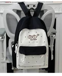 Close-up detail of the black and white canvas backpack with polka dots and transparent front pocket.