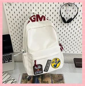 Close-up view of a stylish white canvas backpack featuring creative patches and top letter print.