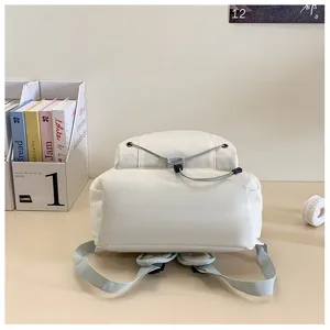 Detail view of a clean white minimalist backpack on a desk, showcasing daily casual style.