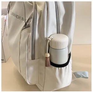 Detail shot of white casual backpack with side pocket and cute tassel, water-resistant.