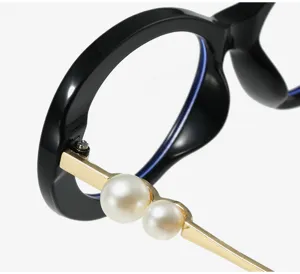 Close-up of black oval optical glasses frame with stylish gold temple and dual pearls.