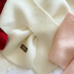 Knit scarf and hat set detail view, showing soft white cross scarf and cozy winter texture close up.