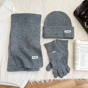 Vue détaillée de l'ensemble bonnet, écharpe et gants en tricot gris avec des touches.