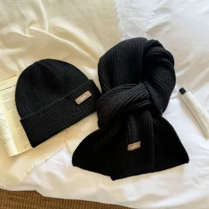 Close-up detail of black knitted beanie hat and scarf set, soft warm winter accessory.