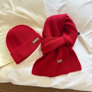 Red knitted scarf and beanie hat set, thick warm winter neck warmer and cozy knit cap detail.