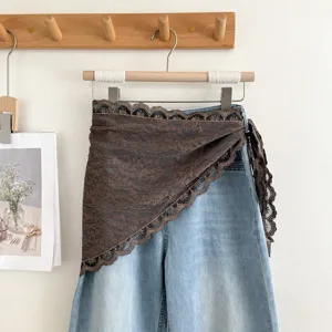 Gedetailleerd overzicht van een bruine kanten wikkelrok over blauwe jeans met mooie details.