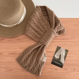 Detail view of brown cable knit cross scarf, soft texture and cozy winter neck warmer close-up.