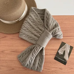 Detail shot of cozy cable knit cross scarf, soft winter neck warmer texture close up.