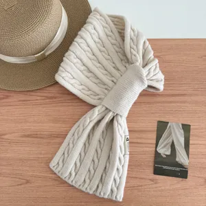 Detailed view of beige cable knit cross neck warmer scarf, cozy autumn winter accessory.