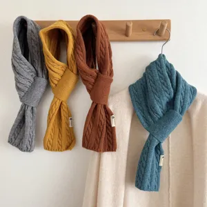 Close-up detail of cozy cable-knit winter scarves in multiple solid colors hanging on hooks.