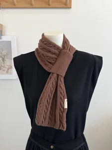 Close-up of brown cable knit cross scarf detail, warm winter neck warmer showing texture.