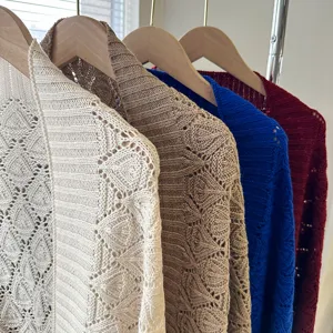 Detailed shot of hollow knit cardigan showing fine diamond texture in multiple colors on hangers.