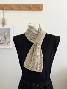Detailed view of the beige cable knit scarf showcasing its unique cross wrap design.