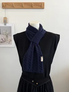 Detailed view of the dark blue cable knit cross scarf, showcasing soft texture and cozy warmth.